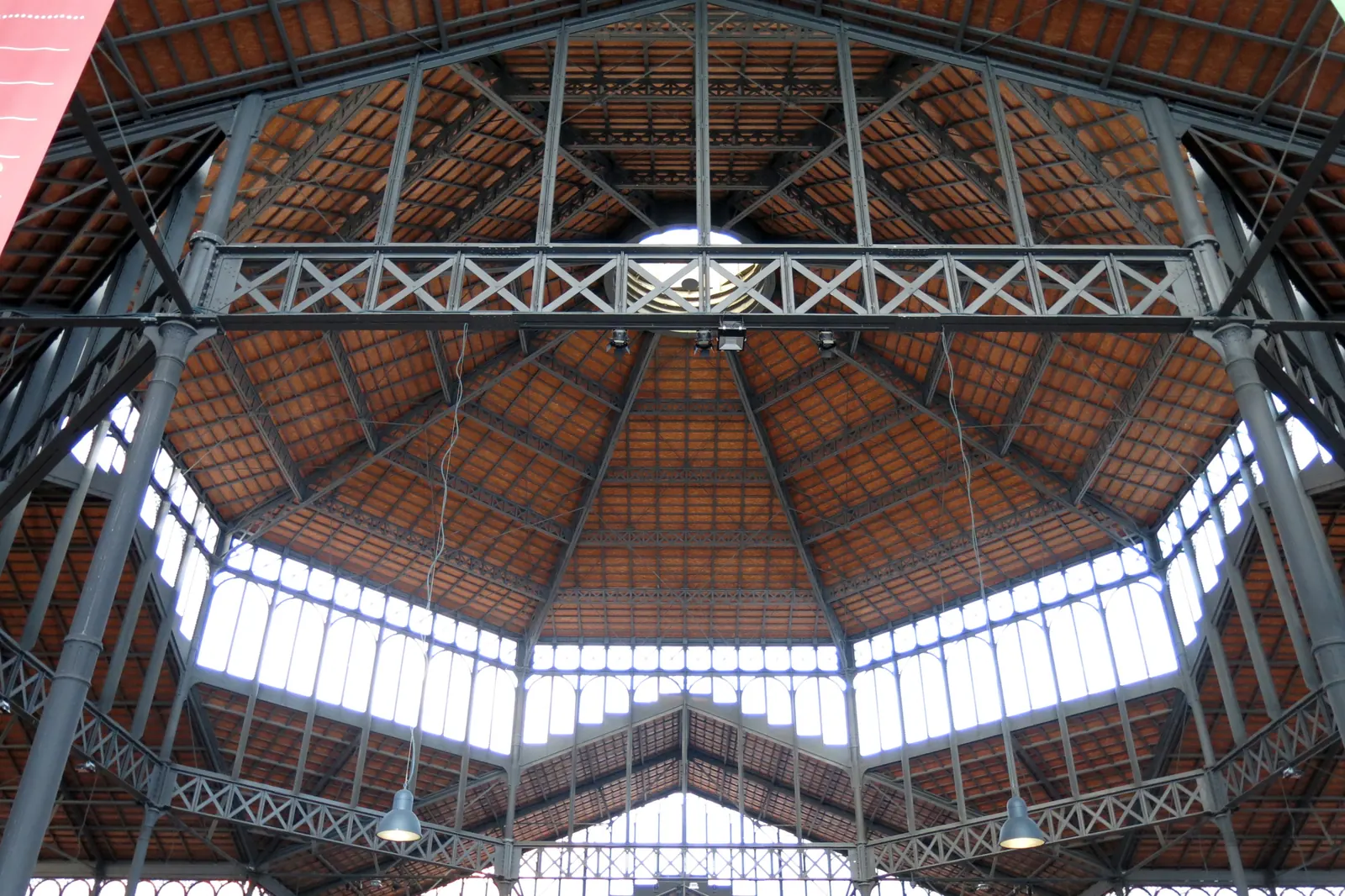 Looking up into the iron and glass roof of the former Mercat del Born, with red-tiled panels and rows of high windows