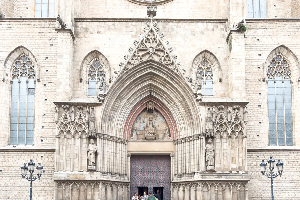 The west portal of Santa Maria del Mar, a pointed Gothic arch with carved statues and a dark wooden door